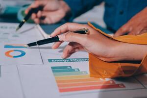 A person is holding a pen and pointing to a chart photo