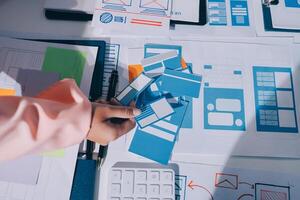 A person is working on a computer with a bunch of paper and blue and white paper photo