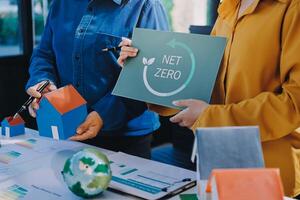 Two people holding up a sign that says net zero photo