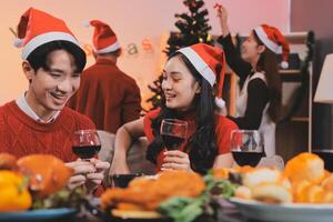 A couple in santa hats drinking wine and eating food photo