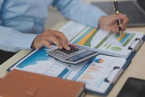 A person is using a calculator and a laptop to do business photo