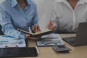 Two business people sitting at a table with a laptop and a book photo