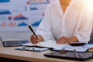 A woman is writing on a piece of paper while sitting at a desk photo