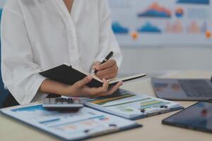 A woman is writing on a notebook while sitting at a desk photo