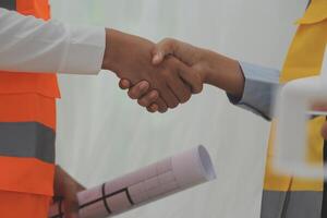 Two people shaking hands while holding construction plans photo