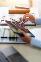 A person using a calculator and a tablet on a desk photo