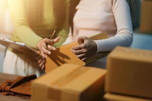 Two women are holding boxes and one is writing on a clipboard photo