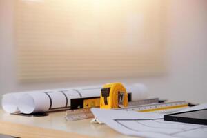 A table with construction plans, a ruler and a tablet photo