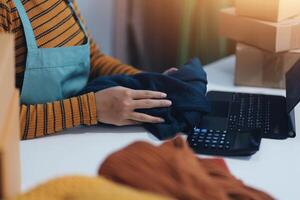 A woman is working on her laptop while holding a package photo