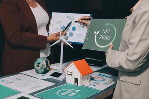 Two people standing around a table with net zero signs photo