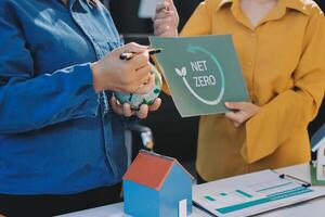 Two people holding up a sign that says net zero photo