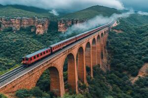 Red train crossing a bridge in a mountainous landscape photo