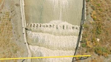 row of chute dentate blocks in concrete water spillway channel slope slowing down splashing flow of water running down video