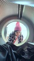 A person is inspecting laundry in a dryer from an unusual angle, adding unique perspective video