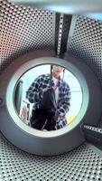 A person is loading clothes into a washing machine while being viewed from the inside perspective video