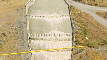 row of chute dentate blocks in concrete water spillway channel slope slowing down splashing flow of water running down video