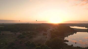 A sunset over a lake with a few hot air balloons video