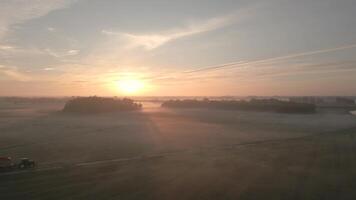 A tractor is driving through a field at sunrise video
