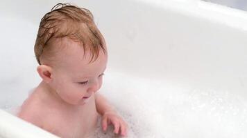 Little boy sitting in a bathtub with soap foam video