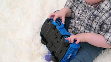 close up hands of a little boy sitting on the sofa playing with a blue car video