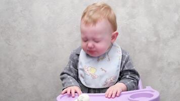 A little boy sitting in a chair at the table sneezes video