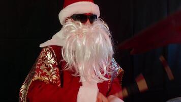 Santa claus with sunglasses and a fake white beard is playing drums during a christmas music show, creating a festive and exciting atmosphere video