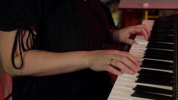 Close-up shots capture a woman's hands skillfully playing a melody on a keyboard synthesizer, showcasing her talent and passion for music in an indoor studio setting video