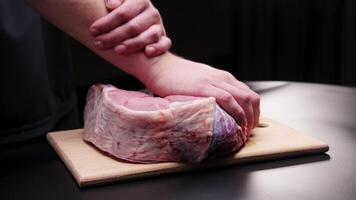 Male hands massaging a large beef steak on a black background. Preparing a tender beef steak for baking. Demonstration of the effect of massage on the body using a piece of meat as an example video