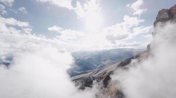 Aerial view cinematic fly through clouds with low clouds lying on rock formations in epic mountainous terrain video