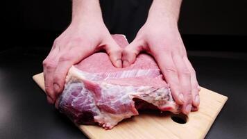Male hands massaging a large beef steak on a black background. Preparing a tender beef steak for baking. Demonstration of the effect of massage on the body using a piece of meat as an example video