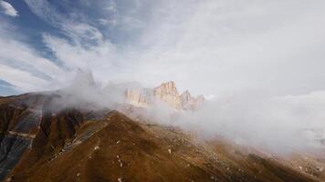 Aerial Cinematic aerial view flight through and alongside low clouds resting on rock formations in an epic mountainous terrain video