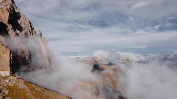 Aerial Cinematic aerial view flight through and alongside low clouds resting on rock formations in an epic mountainous terrain video