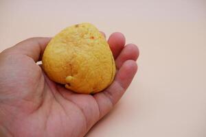Hand Holding an Avocado Seed Against a Warm White-Orange Backgroun photo