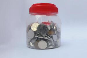 coins stored in small jar isolated on white background photo