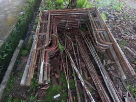 A pile of old rusty steel scaffolding rods lying on the ground photo
