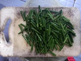 long beans that have been cut into small pieces on a chopping board photo