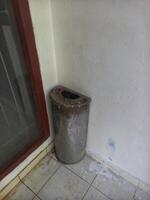 metal trash bin located in the corner of the building photo