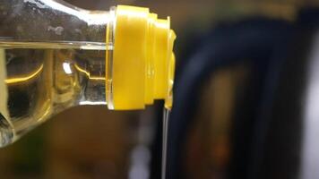 Pouring oil from a yellow bottle into a frying pan for cooking video