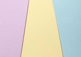 Pastel abstract geometric paper background featuring lavender, yellow, and blue hues arranged in a photo