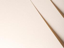 A textured beige paper background featuring overlapping edges and soft shadows, creating depth and photo