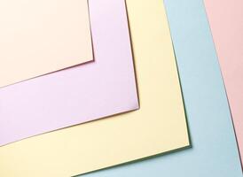 Pastel abstract geometric paper background featuring peach, lavender, yellow, blue, and pink hues in photo