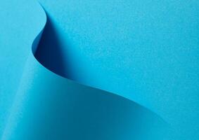 Blue paper background with a smooth matte finish and subtle gradient. Layered geometric accents and photo