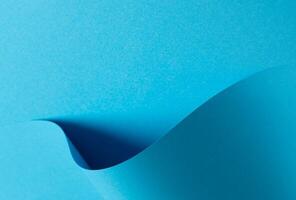 Blue paper background with a smooth matte finish and layered geometric accents. Soft shadows and a photo