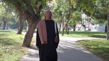 Woman walking through a sunny park path with trees around video