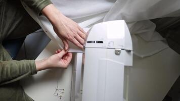 close-up of female hands working on a sewing machine. she carefully watches the work of the sewing machine and the evenness of the stitch, seam. the woman skillfully works on a sewing machine video
