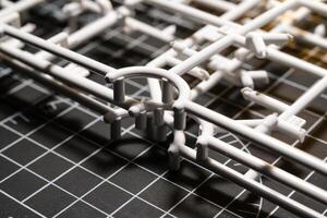 Stack of white Plastic Frames on Black rubber cutting mat. Abstract Backgrounds of model kit frames. Part of plastic model kit and tools for building robot. Miniature, Frame, Plastic, Object photo