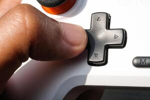 Thumbs pressing buttons on a white gamepad. The game controller buttons are set soft and ergonomic. Finger mechanics and gameplay.. Macrophotography Them photo