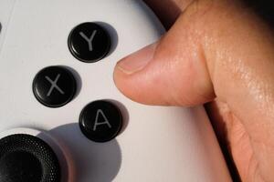 Pressing buttons on a white gamepad. The game controller buttons are set soft and ergonomic. Finger mechanics and gameplay. Hobbies and leisures. Macrophotography Theme photo