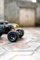 Toy car during outdoor rain with lights on. Remote Control Car being played in the yard during rain. Hobbies and Leisures. Graphic Resources. Toy Photography photo