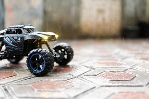 Toy car during outdoor with lights on. Remote Control Car being played in the yard during rain. Hobbies and Leisures. Graphic Resources. Toy Photography Concepts photo